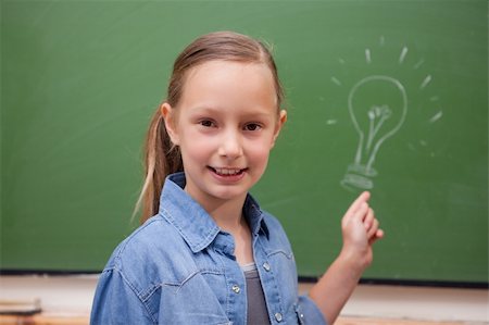Smiling schoolgirl pointing at a bulb on a blackboard Stock Photo - Budget Royalty-Free & Subscription, Code: 400-05894753
