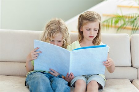 simsearch:400-05751566,k - Siblings reading magazine together on the sofa Stock Photo - Budget Royalty-Free & Subscription, Code: 400-05894889