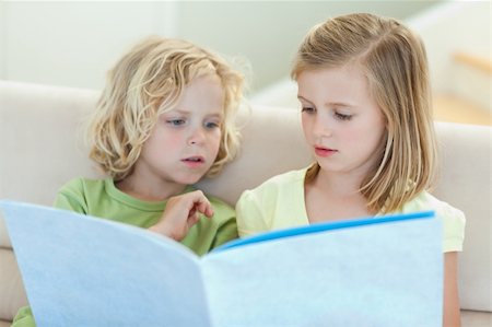 simsearch:400-05751566,k - Siblings reading magazine together on the couch Stock Photo - Budget Royalty-Free & Subscription, Code: 400-05894890