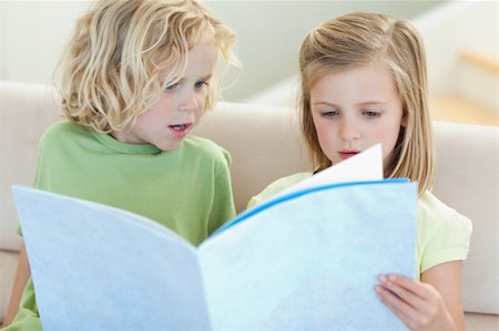 simsearch:400-05751566,k - Siblings on the sofa reading magazine together Stock Photo - Budget Royalty-Free & Subscription, Code: 400-05894891