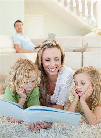 Mother reading magazine together with her children on the floor Stock Photo - Budget Royalty-Free & Subscription, Code: 400-05894915