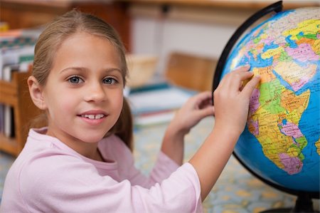 Schoolgirl pointing at a country on a globe Stock Photo - Budget Royalty-Free & Subscription, Code: 400-05895051