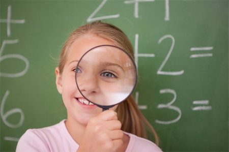 Schoolgirl looking through a magnifying glass against a blackboard Stock Photo - Budget Royalty-Free & Subscription, Code: 400-05895079
