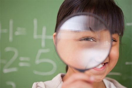 Close up of a cute schoolgirl looking through a magnifying glass in a classroom Stock Photo - Budget Royalty-Free & Subscription, Code: 400-05895084