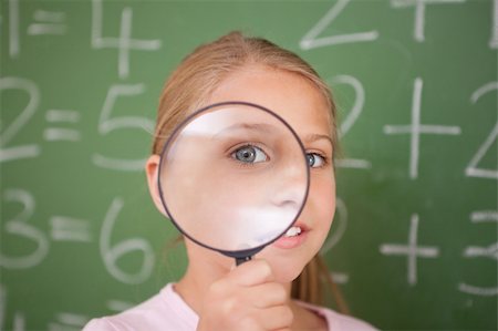 Cute schoolgirl looking through a magnifying glass in a classroom Stock Photo - Budget Royalty-Free & Subscription, Code: 400-05895082