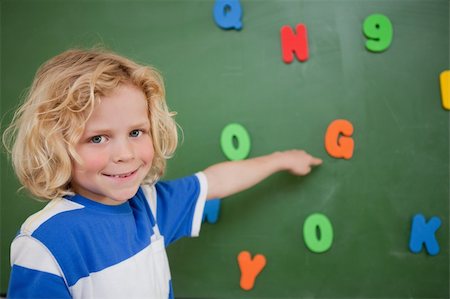Schoolboy pointing at a letter on a blackboard Stock Photo - Budget Royalty-Free & Subscription, Code: 400-05895129