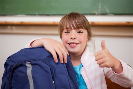 Smiling schoolgirl posing with a bag and the thumb up in a classroom Stock Photo - Budget Royalty-Free & Subscription, Code: 400-05895154
