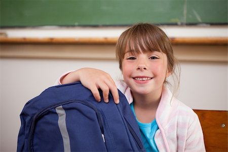 Smiling schoolgirl posing with a bag in a classroom Stock Photo - Budget Royalty-Free & Subscription, Code: 400-05895153