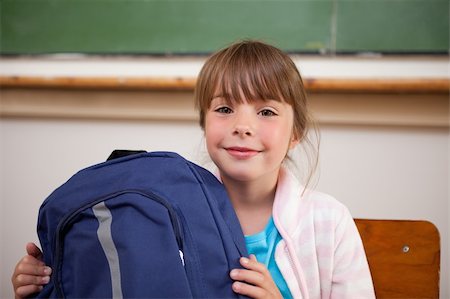 Happy schoolgirl posing with a bag in a classroom Stock Photo - Budget Royalty-Free & Subscription, Code: 400-05895619