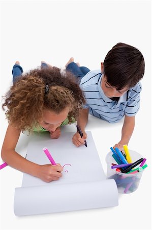 simsearch:6111-06837498,k - Portrait of children drawing while lying on the floor against a white background Stockbilder - Microstock & Abonnement, Bildnummer: 400-05896288