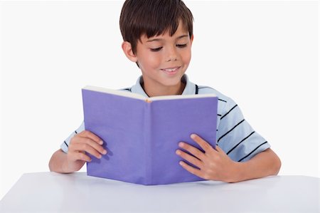 simsearch:400-04434314,k - Smiling boy reading a book against a tablet computer Photographie de stock - Aubaine LD & Abonnement, Code: 400-05896296