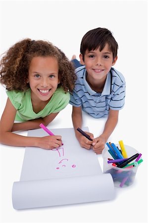 simsearch:6111-06837498,k - Portrait of smiling friends drawing while lying on the floor against a white background Stockbilder - Microstock & Abonnement, Bildnummer: 400-05896291