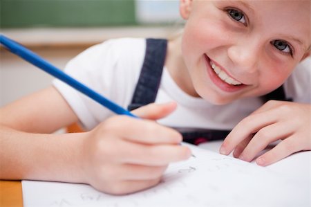 simsearch:400-05329645,k - Close up of a smiling schoolgirl writing something in a classroom Stock Photo - Budget Royalty-Free & Subscription, Code: 400-05896355