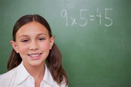 simsearch:400-05894745,k - Smiling schoolgirl posing in front of a chalkboard in a classroom Stockbilder - Microstock & Abonnement, Bildnummer: 400-05896391