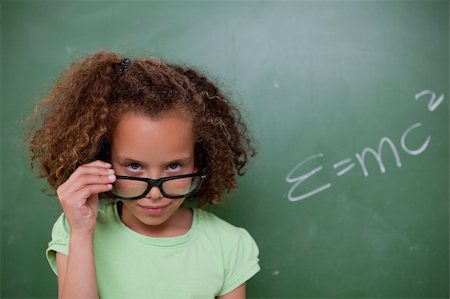 funny looking girls with glasses - Schoolgirl looking above her glasses in front of a blackboard Stock Photo - Budget Royalty-Free & Subscription, Code: 400-05896404