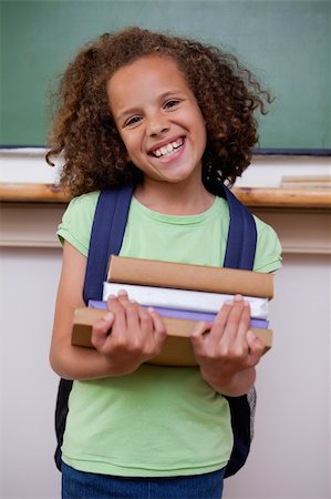 Portrait of a smiling schoolgirl holding her books in a classroom Stock Photo - Budget Royalty-Free & Subscription, Code: 400-05896420