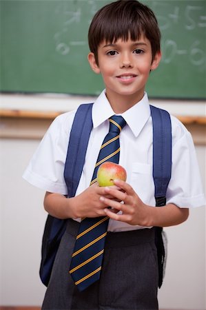 school food bag - Portrait of a schoolboy holding an apple in a classroom Stock Photo - Budget Royalty-Free & Subscription, Code: 400-05896545