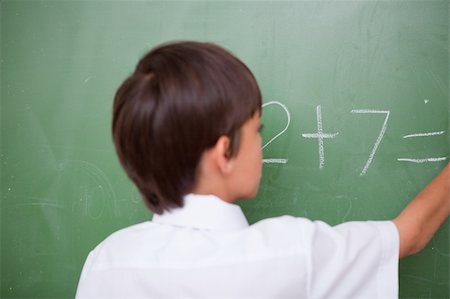 student writing on board - Little schoolboy writing an addition on a chalkboard Stock Photo - Budget Royalty-Free & Subscription, Code: 400-05896547