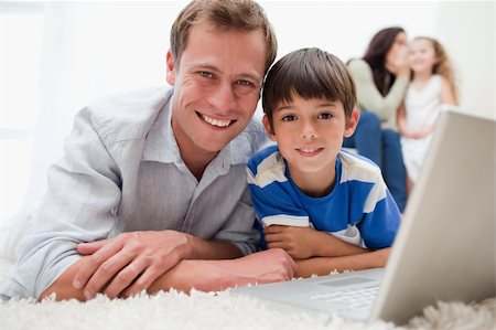 simsearch:400-05897773,k - Smiling son and dad using laptop together on the carpet Stock Photo - Budget Royalty-Free & Subscription, Code: 400-05896579