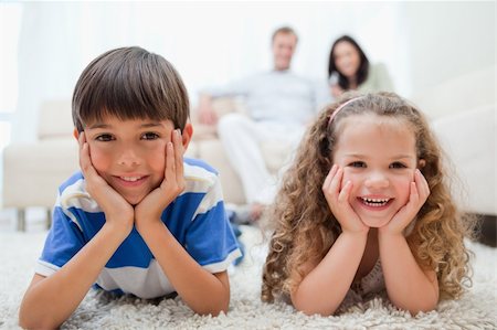 simsearch:400-05897773,k - Happy smiling kids lying on the carpet with parents behind them Stock Photo - Budget Royalty-Free & Subscription, Code: 400-05896570