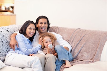 family laughing and relaxing on sofa - Happy young family watching television together Stock Photo - Budget Royalty-Free & Subscription, Code: 400-05897774