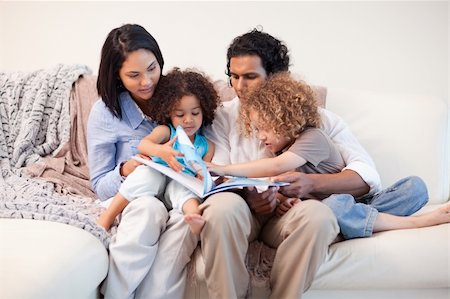 simsearch:400-05897773,k - Young family on the sofa looking at the photo album together Stock Photo - Budget Royalty-Free & Subscription, Code: 400-05897780