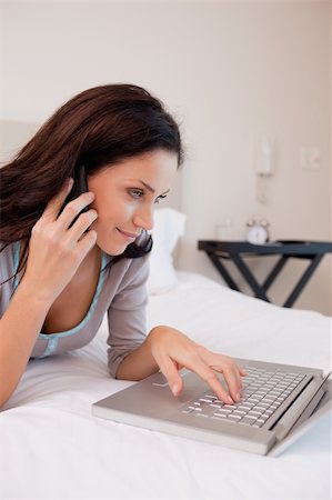 simsearch:400-05737165,k - Side view of young woman on the bed with cellphone and laptop Stock Photo - Budget Royalty-Free & Subscription, Code: 400-05897944