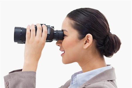 simsearch:400-04632747,k - Side view of a businesswoman looking through binoculars against a white background Fotografie stock - Microstock e Abbonamento, Codice: 400-05898634