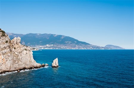 Beautiful rock on the Black Sea shore with clear blue sky and town on background Stock Photo - Budget Royalty-Free & Subscription, Code: 400-05898755