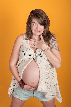 Embarrassed young pregnant woman looks away and bites lip Stock Photo - Budget Royalty-Free & Subscription, Code: 400-05898841
