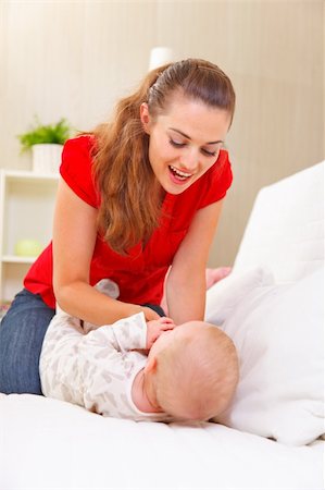 simsearch:400-05899075,k - Young mother playing with baby on divan Fotografie stock - Microstock e Abbonamento, Codice: 400-05899076