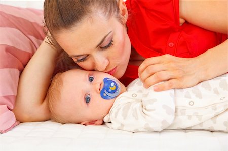 simsearch:400-06086432,k - Young mother laying on couch and kissing baby Stockbilder - Microstock & Abonnement, Bildnummer: 400-05899071