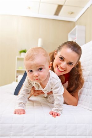 simsearch:400-05899075,k - Happy mother and interested baby playing on divan Fotografie stock - Microstock e Abbonamento, Codice: 400-05899081
