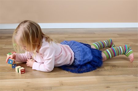Little girl lying on her tummy building blocks Stock Photo - Budget Royalty-Free & Subscription, Code: 400-05890866