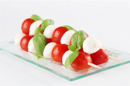 Cherry tomatoes and mozzarella on skewers, garnished with basil leaves and olive oil Stock Photo - Budget Royalty-Free & Subscription, Code: 400-05890952