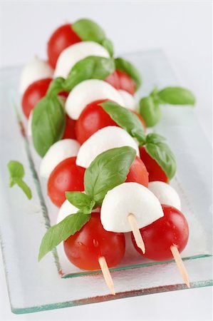 Cherry tomatoes and mozzarella on skewers, garnished with basil leaves and olive oil Stock Photo - Budget Royalty-Free & Subscription, Code: 400-05890953