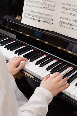 Photo of a young girl playing the piano with sheet music open. Stock Photo - Budget Royalty-Free & Subscription, Code: 400-05892042