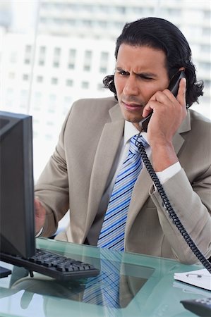 simsearch:6116-08915424,k - Portrait of a confused businessman working with a monitor while being on the phone in his office Foto de stock - Super Valor sin royalties y Suscripción, Código: 400-05892344