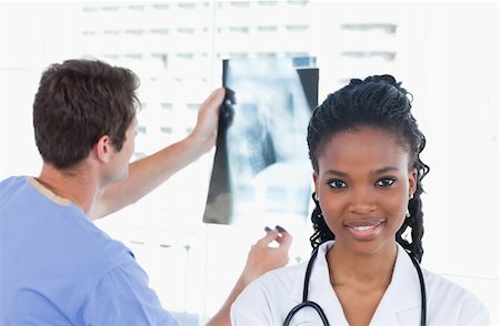 Doctor looking at a of X-ray while his colleague is posing in an office Stock Photo - Budget Royalty-Free & Subscription, Code: 400-05892431