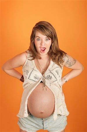 simsearch:400-05918412,k - Sassy pregnant woman with hands on hip over orange background Foto de stock - Royalty-Free Super Valor e Assinatura, Número: 400-05904528