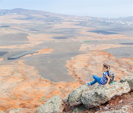 Young girl sitting with backpack on cliff's edge and looking to a sky. Lanzarote Foto de stock - Super Valor sin royalties y Suscripción, Código: 400-05905546
