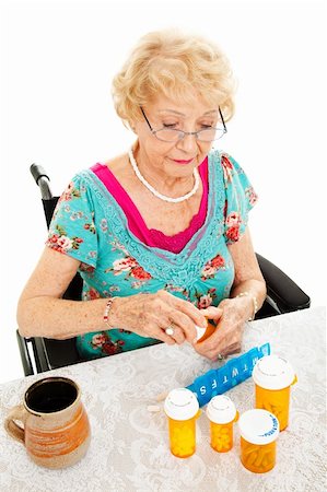 pillbox - Disabled senior woman in a wheelchair, counting out her medications for the week.  White background. Stock Photo - Budget Royalty-Free & Subscription, Code: 400-05906323