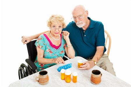 elderly couple concern - Senior couple frustrated by health issues, sitting at the table surrounded by pill bottles.  Isolated on white. Stock Photo - Budget Royalty-Free & Subscription, Code: 400-05906332