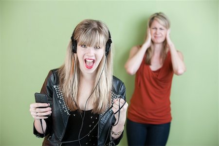 Excited retro-styled woman sings out loud with annoyed mom behind her Stock Photo - Budget Royalty-Free & Subscription, Code: 400-05907916