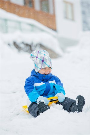 Cute little boy in blue riding on a sled near  the Austrian cottage Foto de stock - Super Valor sin royalties y Suscripción, Código: 400-05909254