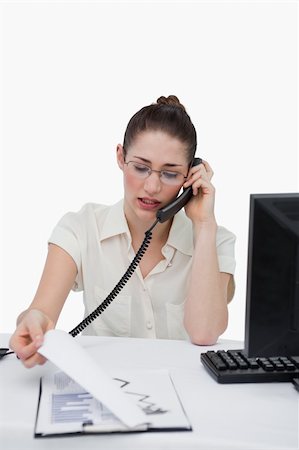 Portrait of a businesswoman making a phone call while looking at statistics against a white background Stock Photo - Budget Royalty-Free & Subscription, Code: 400-05900627