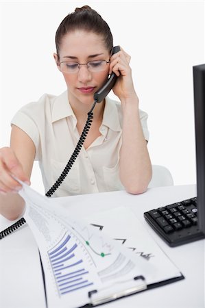 Portrait of a serious manager making a phone call while looking at statistics against a white background Stock Photo - Budget Royalty-Free & Subscription, Code: 400-05900631