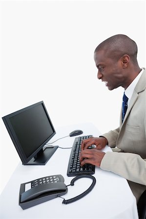 sad black person computer - Side view of an angry businessman using a computer against a white background Photographie de stock - Aubaine LD & Abonnement, Code: 400-05900663