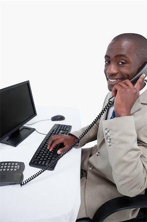 simsearch:400-06393704,k - Side view of a male secretary answering the phone while using a monitor against a white background Stockbilder - Microstock & Abonnement, Bildnummer: 400-05900674