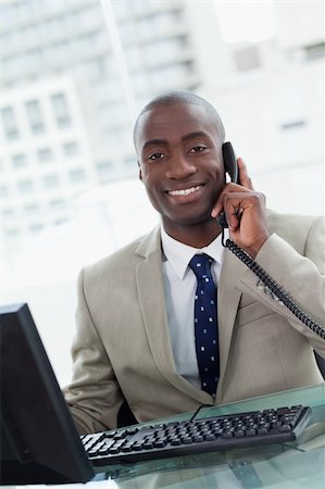 simsearch:400-05900712,k - Portrait of a smiling office worker making a phone call  while using a computer Stock Photo - Budget Royalty-Free & Subscription, Code: 400-05900711